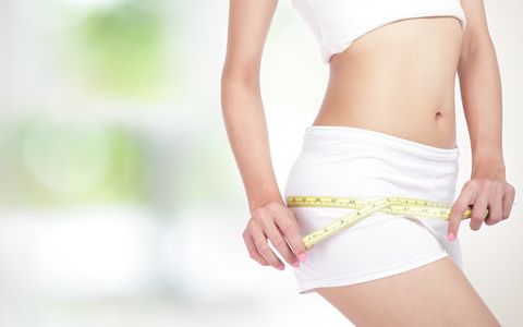 close up of Young Woman measuring perfect shape of beautiful hips. Healthy lifestyles concept, with green background